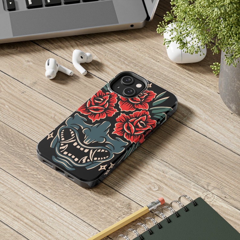 May include: Black phone case with a graphic design of a red and green floral pattern and a blue and white demon face.