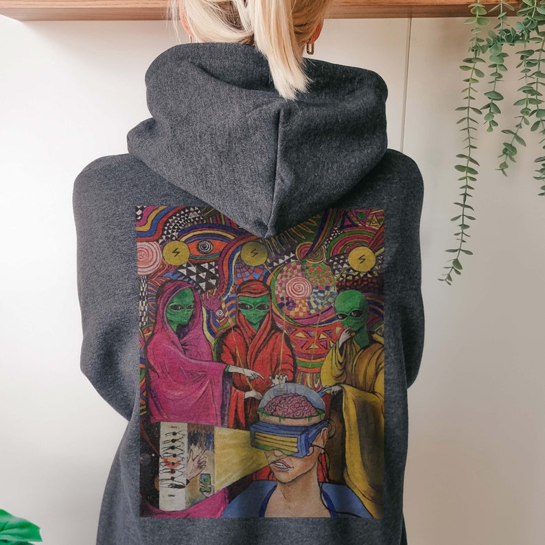 Puede incluir: Una sudadera con capucha gris oscuro con un estampado gr&aacute;fico colorido en la espalda. El estampado presenta cuatro figuras extraterrestres con ojos brillantes, una figura humana con el cerebro expuesto y un fondo psicod&eacute;lico.