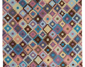 May include: A colorful rug with a geometric pattern of squares and diamonds in shades of pink, blue, brown, and beige.