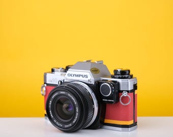 Olympus OM10 Slr Vintage 35mm Filmkamera mit Zuiko 50mm f1.8 Festbrennweite und manuellem Adapter mit neuer Lederrot und Gelber Haut