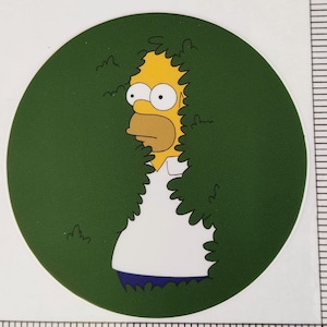 May include: A yellow cartoon character with a white shirt and blue pants is peeking out from behind a green bush. The character has a surprised expression on its face.