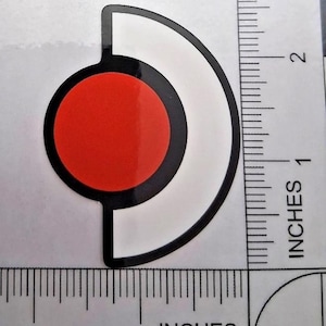 May include: A sticker featuring a red circle within a black outline, and a white semi-circular shape. The sticker measures approximately 2.5 cm wide and 2.5 cm tall.