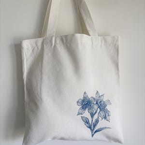 a white canvas tote bag with minimalist blue Orchids flower print