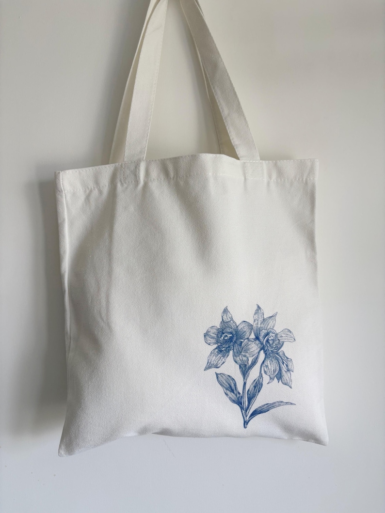 a white canvas tote bag with minimalist blue Orchids flower print