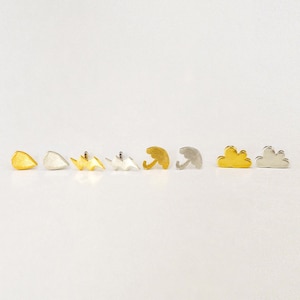 Può includere: Una collezione di orecchini a lobo a tema meteo. Gli orecchini includono forme di goccia di pioggia, fulmine, ombrello e nuvola. Gli orecchini sono in tonalità oro e argento, con un design minimalista.