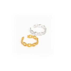 May include: Two toe rings, one gold-colored and one silver-colored, are displayed against a white background. Each ring features an open design with an interwoven pattern. The gold ring is positioned in the foreground, with the silver ring behind it.