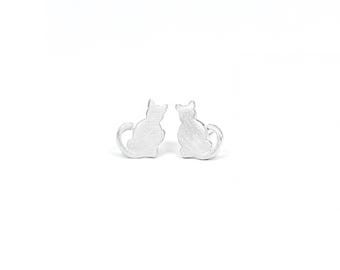May include: A pair of silver cat silhouette stud earrings.