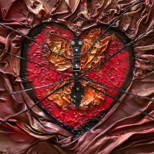 Könnte beinhalten: Ein Mixed-Media-Kunstwerk mit einer Herzform in Rot und Schwarz, mit einem zentralen Schmetterlingsdesign. Das Herz ist mit strukturiertem Stoff und schwarzen Linien verziert, und der Schmetterling hat ein lederartiges Aussehen.