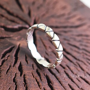 Peut inclure: Une bague en argent avec un motif géométrique de triangles. La bague est simple et élégante.