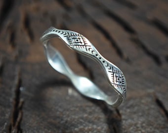 May include: A silver ring with a geometric design. The ring is made of a smooth, shiny metal and has a wavy shape.