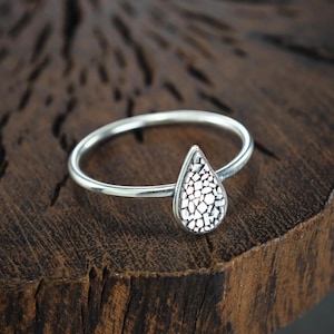 Op de afbeelding: Een zilveren ring met een getextureerd druppelvormig ontwerp.