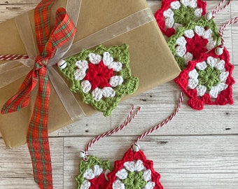 May include: Five crocheted Christmas tree ornaments in red, white, and green with small bells attached. The ornaments are on a brown paper wrapped gift box with a red and green plaid ribbon.