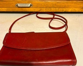 May include: A red leather crossbody purse with a flap closure and a long strap.