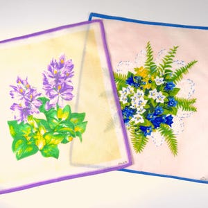 Op de afbeelding: Twee vintage bloemmotieven zakdoekjes. Eén is geel met paarse bloemen en groene bladeren. De andere is roze met een boeket witte, blauwe en gele bloemen.