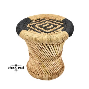 May include: A round, woven stool with a black and natural colored rope top. The stool is made of natural woven bamboo.
