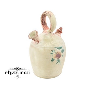 Puede incluir: Una jarra de cerámica blanca con un diseño floral. La jarra tiene un asa y un pico. Es una jarra de estilo tradicional.