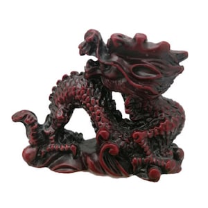 Op de afbeelding: Een rood en zwart drakenbeeldje met ingewikkelde details. De draak is opgerold in een verdedigende positie met zijn kop omhoog en zijn klauwen uitgestoken.
