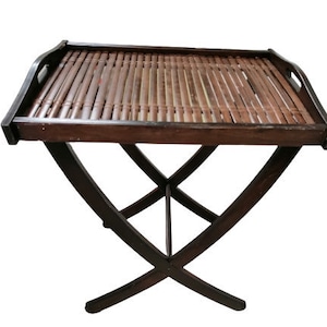 May include: A brown wooden folding table with a bamboo top. The table has a simple design with a rectangular top and a cross-shaped base.