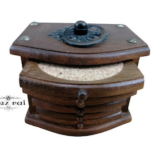 Op de afbeelding: Een set van zes houten onderzetters met een decoratieve houten doos. De doos heeft een scharnierend deksel met een metalen handvat. De onderzetters zijn gemaakt van kurk en hebben een natuurlijke houten afwerking.