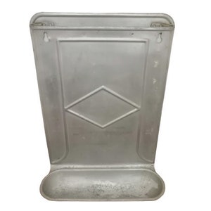 Puede incluir: Un estante de pared de metal plateado con un patr&oacute;n de diamante y un peque&ntilde;o estante en la parte inferior.