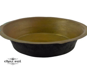 Może przedstawiać: Okrągła miedziana miska z czarnym brzegiem. Miska jest pusta i ma błyszczącą powierzchnię.