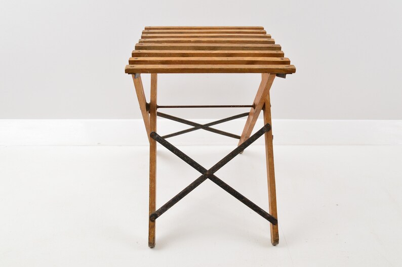 May include: A wooden folding table with a slatted top and black metal supports. The table is made of natural wood and has a rustic look.
