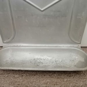 Puede incluir: Un portacepillos de dientes de metal plateado montado en la pared con una peque&ntilde;a bandeja rectangular en la parte inferior.
