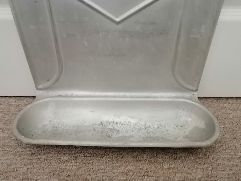 Puede incluir: Un portacepillos de dientes de metal plateado montado en la pared con una peque&ntilde;a bandeja rectangular en la parte inferior.