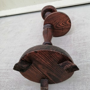 K&ouml;nnte beinhalten: Ein dunkelbrauner Kerzenst&auml;nder aus Holz mit runder Basis und drei Beinen. Der Kerzenst&auml;nder hat ein dekoratives Design auf der Oberseite und eine runde Plattform f&uuml;r die Kerze.