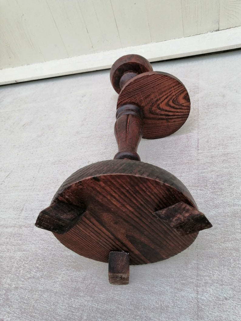 K&ouml;nnte beinhalten: Ein dunkelbrauner Kerzenst&auml;nder aus Holz mit runder Basis und drei Beinen. Der Kerzenst&auml;nder hat ein dekoratives Design auf der Oberseite und eine runde Plattform f&uuml;r die Kerze.