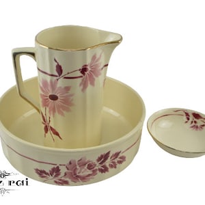 Könnte beinhalten: Cremefarbenes Keramik-Krug-, Becken- und kleines Schalenset. Krug und Becken sind mit rosa Blumendesigns verziert. Der Krug hat einen goldenen Rand und Griff. Becken und Schale haben einen rosa Blumenrand. Ein dekoratives Vintage-Set.