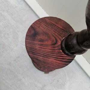 K&ouml;nnte beinhalten: Ein Holzsockel mit runder Oberseite und gedrehtem Fu&szlig;. Der Sockel ist in einem dunklen Rotbraun gebeizt.