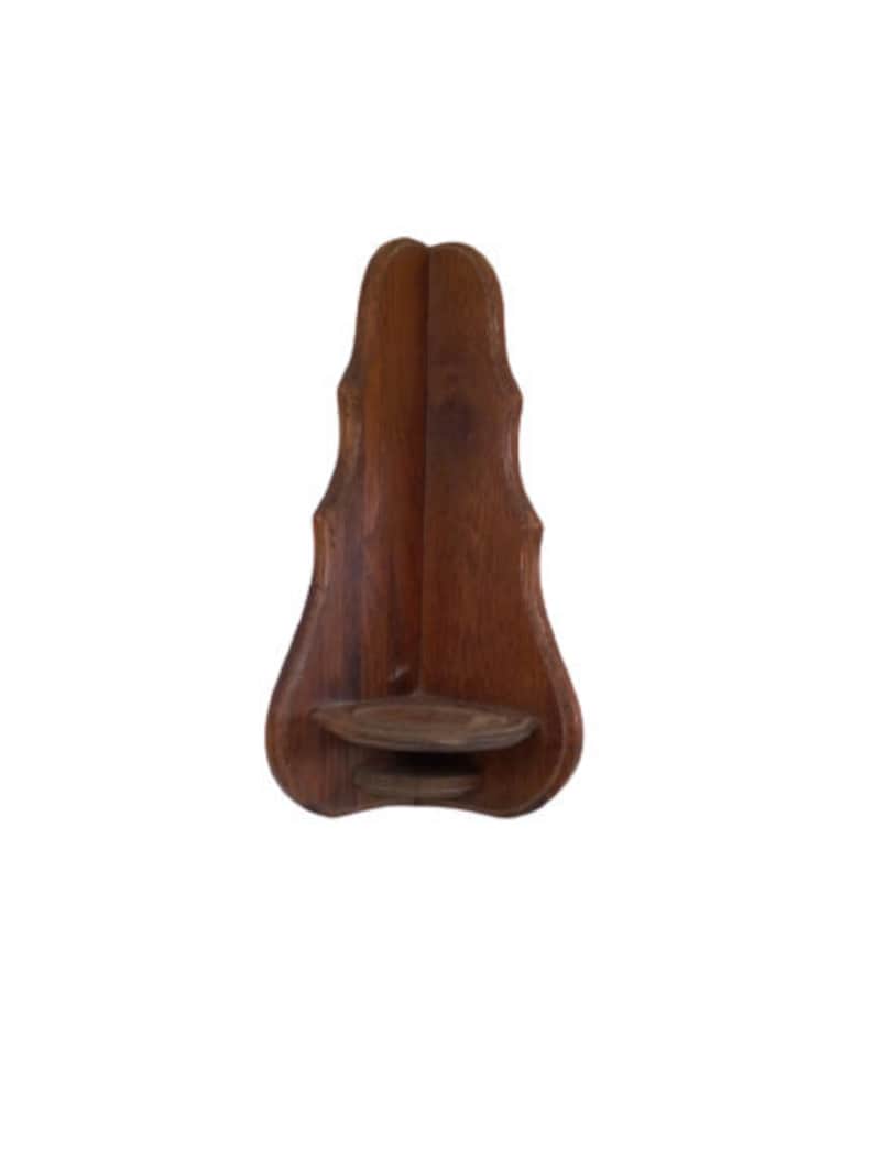 May include: A dark brown wooden wall mount shelf with a decorative, scalloped edge. The shelf has a small, rectangular ledge.