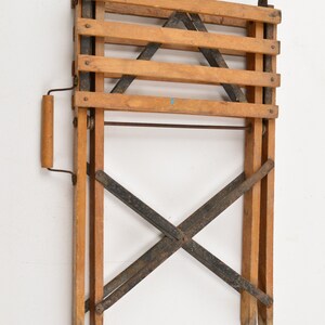 May include: A wooden folding chair with a metal frame. The chair is folded and has a wooden handle.