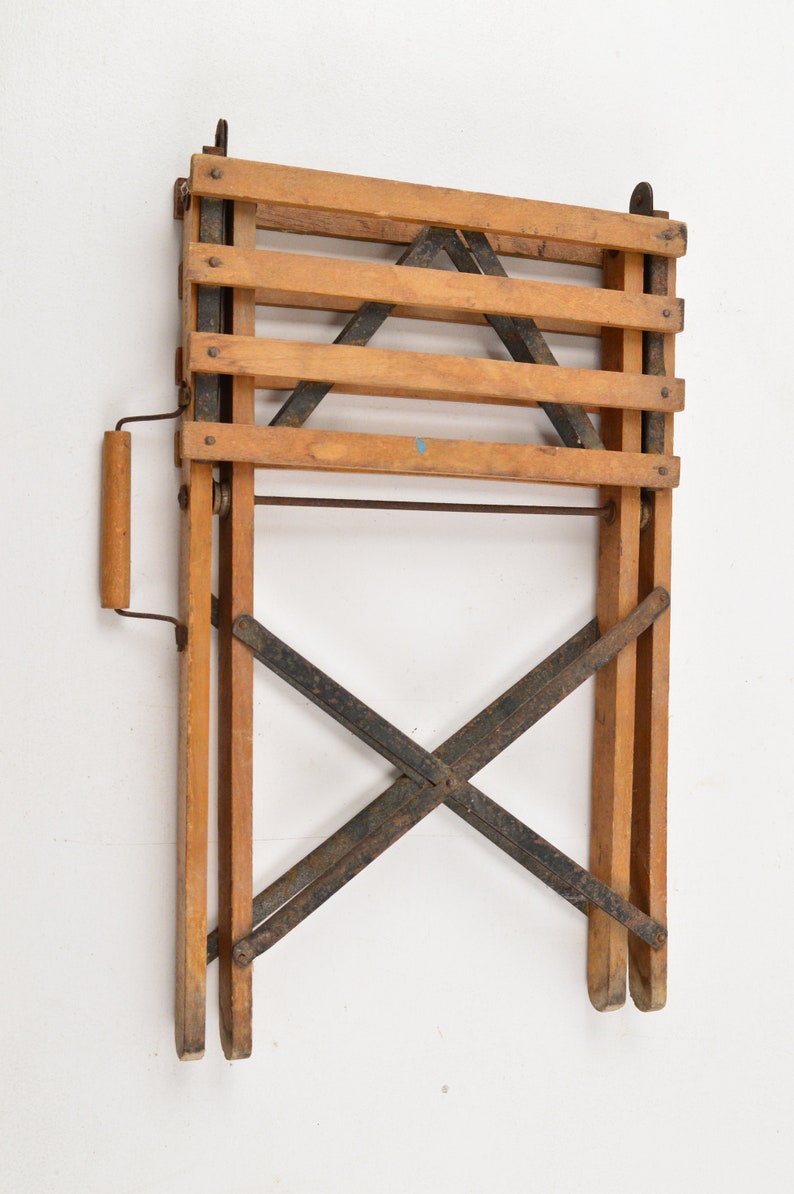 May include: A wooden folding chair with a metal frame. The chair is folded and has a wooden handle.