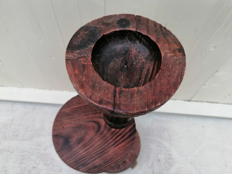 K&ouml;nnte beinhalten: Ein Holzsockel mit einer runden Oberseite und einer kleineren runden Basis. Die Oberseite ist dunkelbraun und hat einen leicht erh&ouml;hten Rand. Die Basis ist hellbraun und hat eine glatte Oberfl&auml;che.