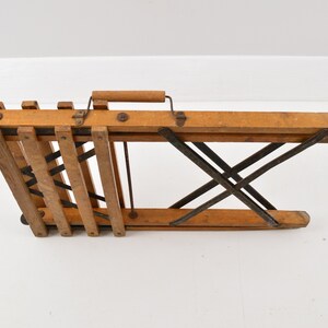 May include: A wooden folding chair with a metal frame. The chair is folded up and has a wooden handle.