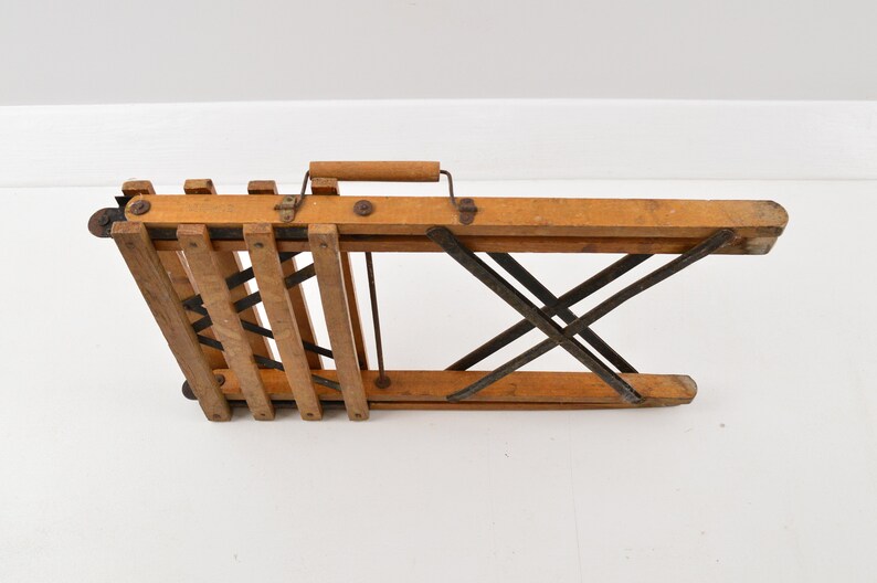May include: A wooden folding chair with a metal frame. The chair is folded up and has a wooden handle.