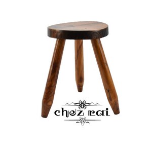 May include: A wooden stool with three legs and a round top. The stool is made of dark wood and has a natural finish.