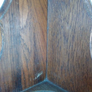 May include: Close-up of the corner of a wooden shelf with a dark brown stain. The wood grain is visible and the shelf has a slightly worn appearance.