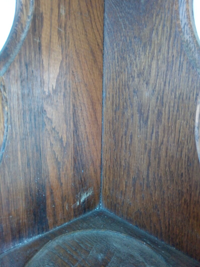 May include: Close-up of the corner of a wooden shelf with a dark brown stain. The wood grain is visible and the shelf has a slightly worn appearance.