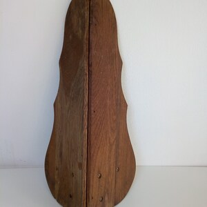 May include: A wooden, triangular-shaped wall decor with a dark brown finish. The decor has a unique, curved design and is made of two pieces of wood that are joined together.