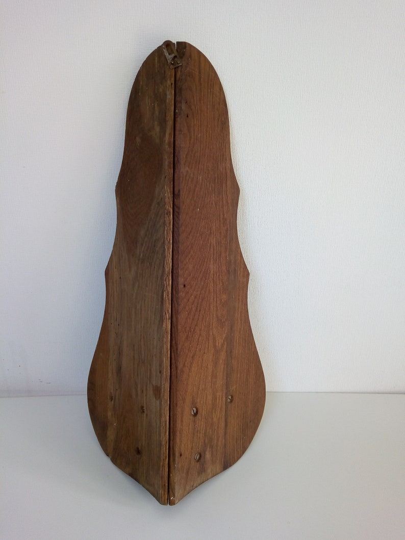 May include: A wooden, triangular-shaped wall decor with a dark brown finish. The decor has a unique, curved design and is made of two pieces of wood that are joined together.