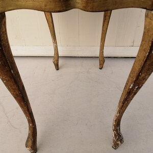May include: A pair of gold-painted wooden side tables with ornate legs. The tables are distressed and have a vintage look.