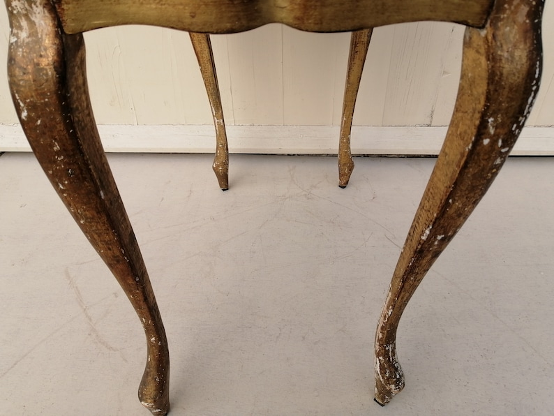 May include: A pair of gold-painted wooden side tables with ornate legs. The tables are distressed and have a vintage look.