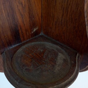 May include: A wooden corner shelf with a carved design on the front. The shelf is made of dark wood and has a rustic look.