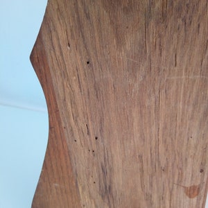 May include: A close-up of a wooden shelf with a unique, curved shape. The wood has a natural, rustic finish with visible knots and grain.