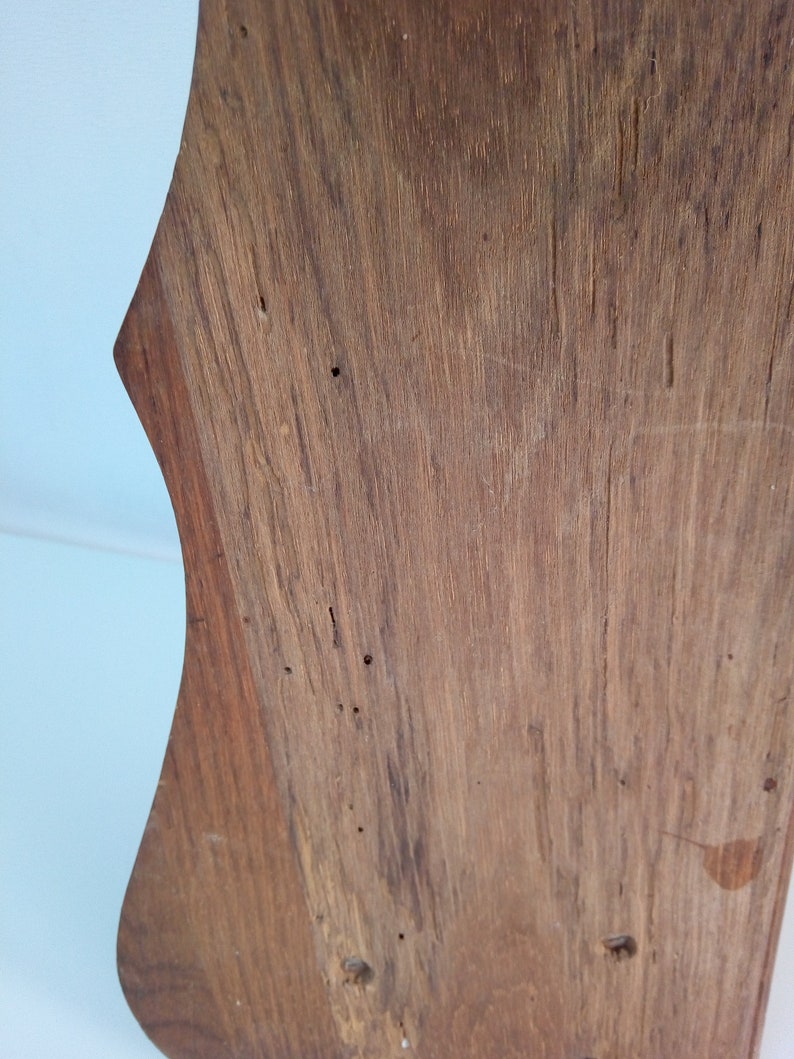 May include: A close-up of a wooden shelf with a unique, curved shape. The wood has a natural, rustic finish with visible knots and grain.