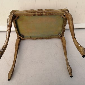 May include: A small, ornate, wooden table with a light brown finish and carved details. The table has four legs and a rectangular top.