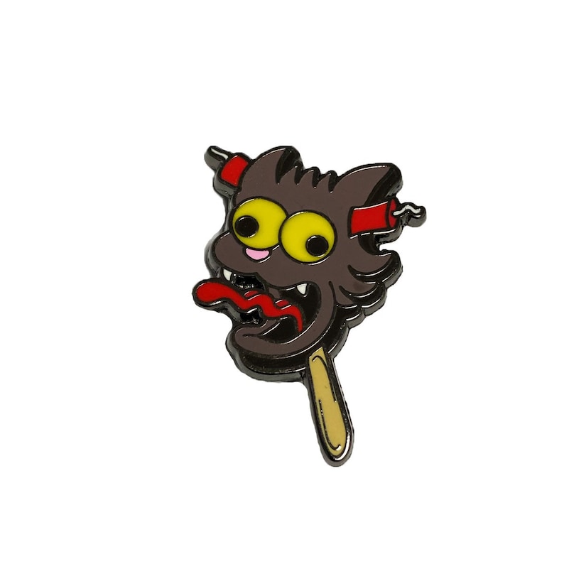 May include: A black and brown cartoon cat head with yellow eyes and a red tongue sticking out. The cat is on a stick with a red and white striped design.